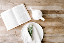 opened Bible on a table and plate and napkin 