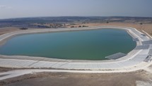 Aerial shot of an agricultural water reservoir surrounded by fields. Irrigation concept