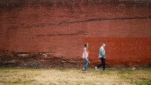 a couple walking in front of a brick building 