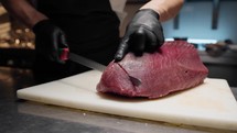 Chef slices salmon for sushi in a Japanese restaurant
