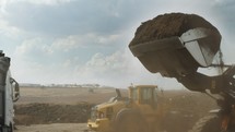 Industrial compost production site. Tractors loading compost into screening machines and trucks