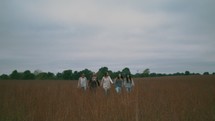 women walking through a field of tall grasses