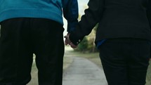 an elderly couple walking holding hands 