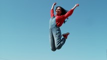 woman jumping up for joy against a blue sky