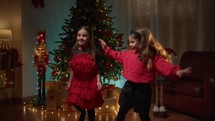 Young sisters girls dancing under the Christmas tree 
