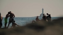old lighthouse with beach and people in the foreground