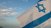 Waving Israel Flag on sunset ocean