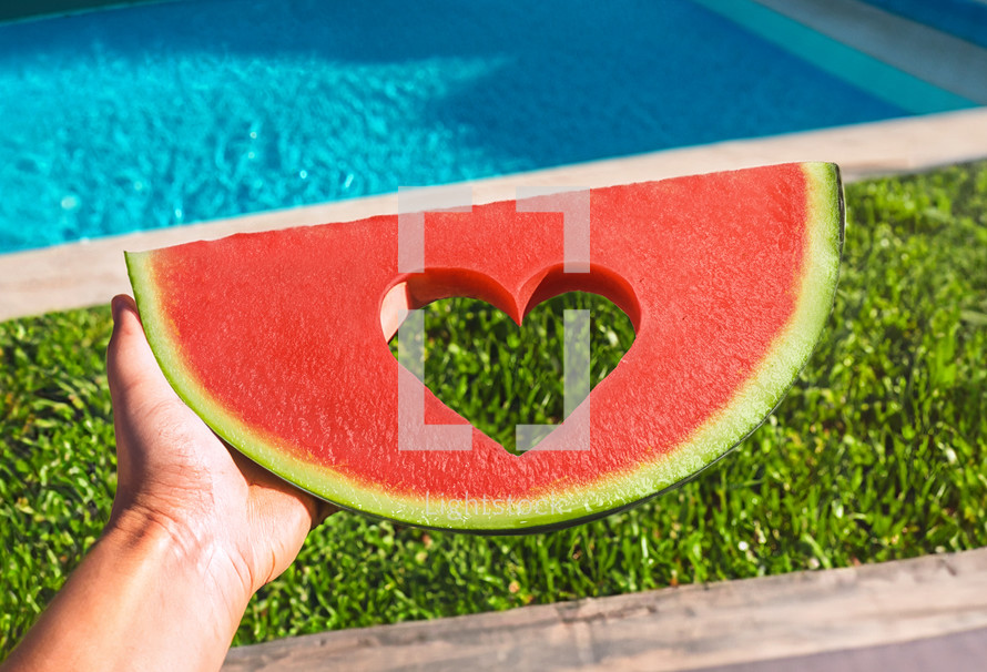 Slice of watermelon with heart and without seeds in the pool in summer.