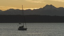 Sailboats on water as sunset lights fades with mountains in the background