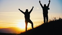 Silhouette tourists on hike with backpacks and equipment climbed on high mountain. Raise your hands up. Achieving set goal. Victory over yourself and great endurance and willpower. Sport lifestyle.