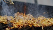 Close up of chicken breast roasted on a grill with flames.
