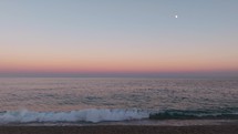 Red sunset and moon in the romantic sky on the ocean water