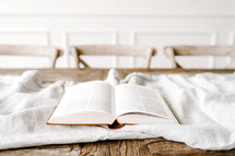 opened Bible on a white blanket on a table 