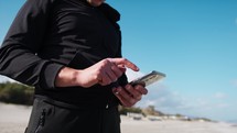 Hand Of A Boy Texts With Phone On The Beach