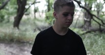 Young man, teenage boy walking in slow motion outside in woods and trees.