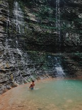 child standing under a waterfall 
