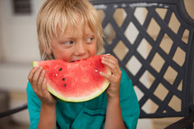 boy child eating a watermelon on a summer day 