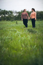 mother and daughter holding hands in a field 