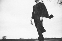 Graduate walking with a Bible.