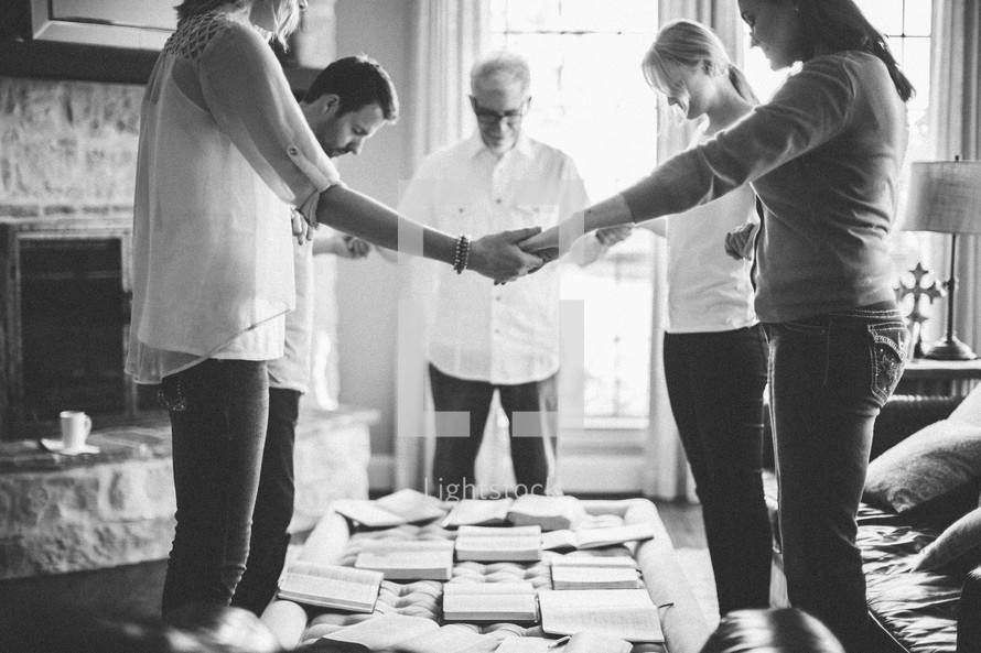 Men and women holding hands in a prayer circle during a Bible study.