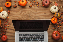 laptop computer surrounded by fall decorations 