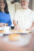 man and woman standing at a table next to coffee, donuts, and Bibles 