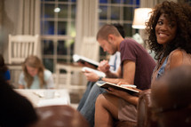 A black young adult woman smiling during a Bible study.