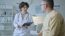 Female Doctor Questioning Patient and Taking Notes during Medical Check-Up
