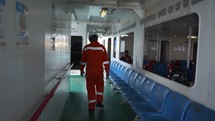 Asian Man working on ship walks past passengers Ferry Workers
