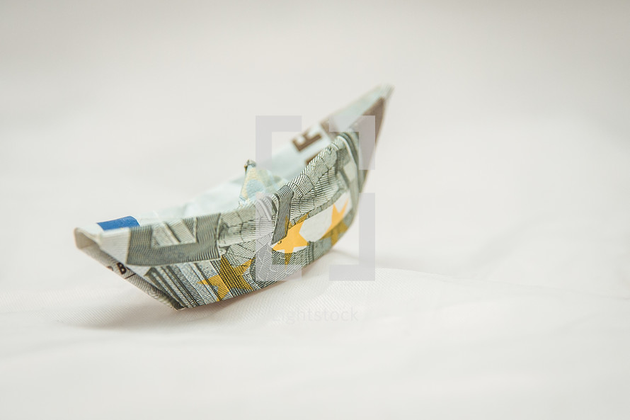 paper origami boat made of money on a white background 