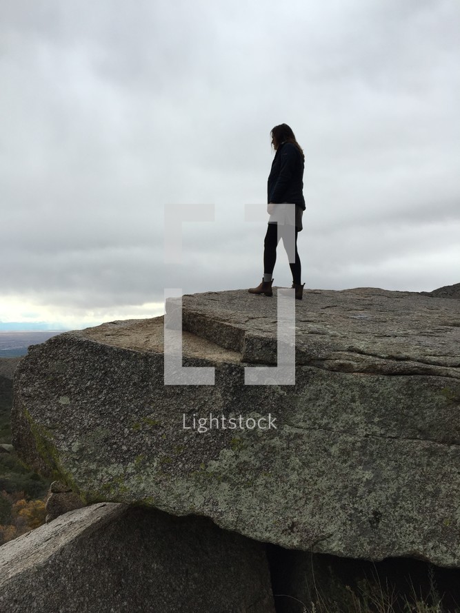 a woman standing on the edge of a rock cliff 