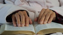 A woman's hands while reading the Bible and praying