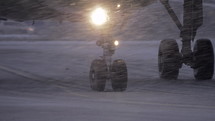 Slow motion shot of airplane wheels moving on runaway. View in evening blizzard