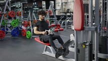 Intensive workout in gym, man doing cable row exercise.