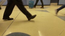 People rushing by with luggage at an airport concourse