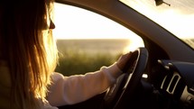 Blonde woman getting into car and startting car on the coast during golden hour.
