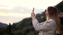 Long haired woman takes a photo with a smartphone in her hands.
