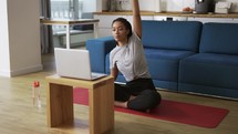 Young African woman doing stretching, warming up her joints in front laptop, slow motion.