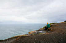 a woman sitting at the edge of a cliff 