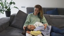 Mother and small daughter bonding together on the sofa.