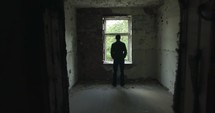 man standing at a window in an abandoned building 