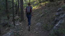 A young woman hiking on a rocky trail in the forest