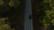 Car Driving Down Empty Rural Road in the Country at Sunset. Aerial footage following car driving on a country road in Mississippi
