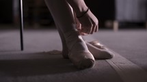 ballerina tying her toe shoes 