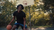 Young man dribbling a basketball on an outdoor court on a sunny day