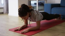 African american young sportswoman doing plank exercise at home.