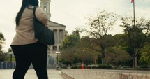 Young business woman walking around the city using her phone and laptop