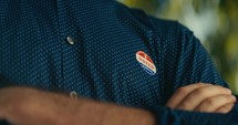 Young man smiling with an ‘I Voted’ sticker and pin 