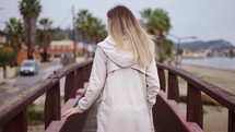 Blonde woman walking on small wooden bridge in a small city.