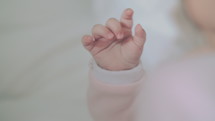 A closeup of a tiny baby girl's hand moving around.